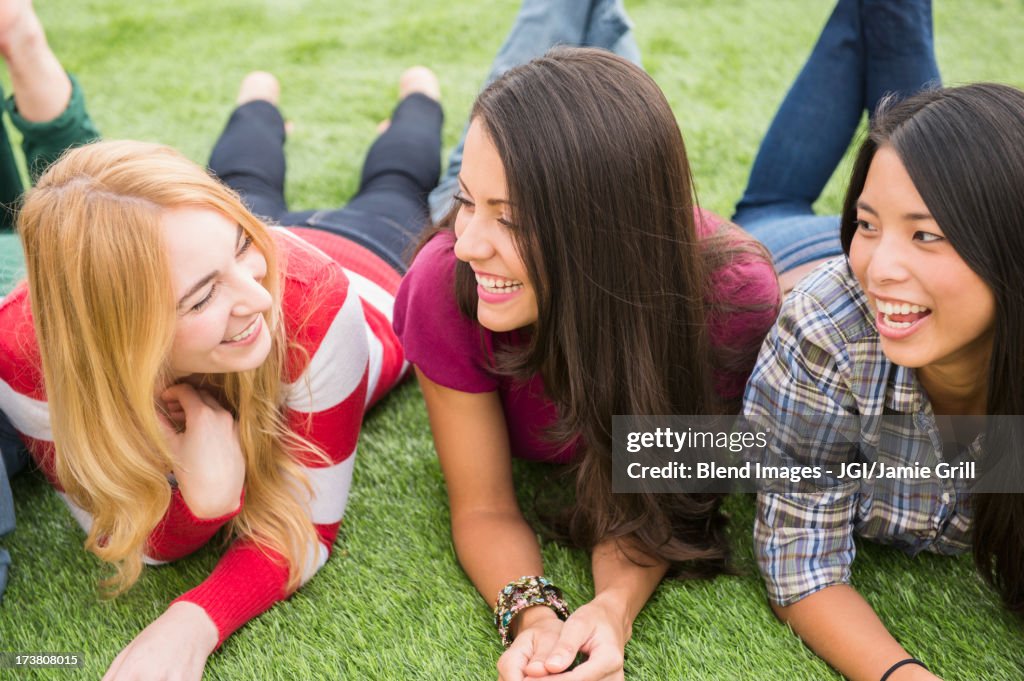 Smiling women laying in grass together