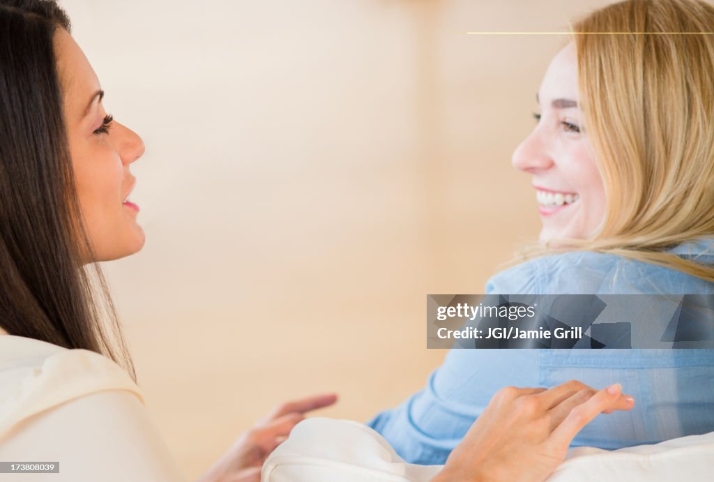 Smiling women talking on sofa