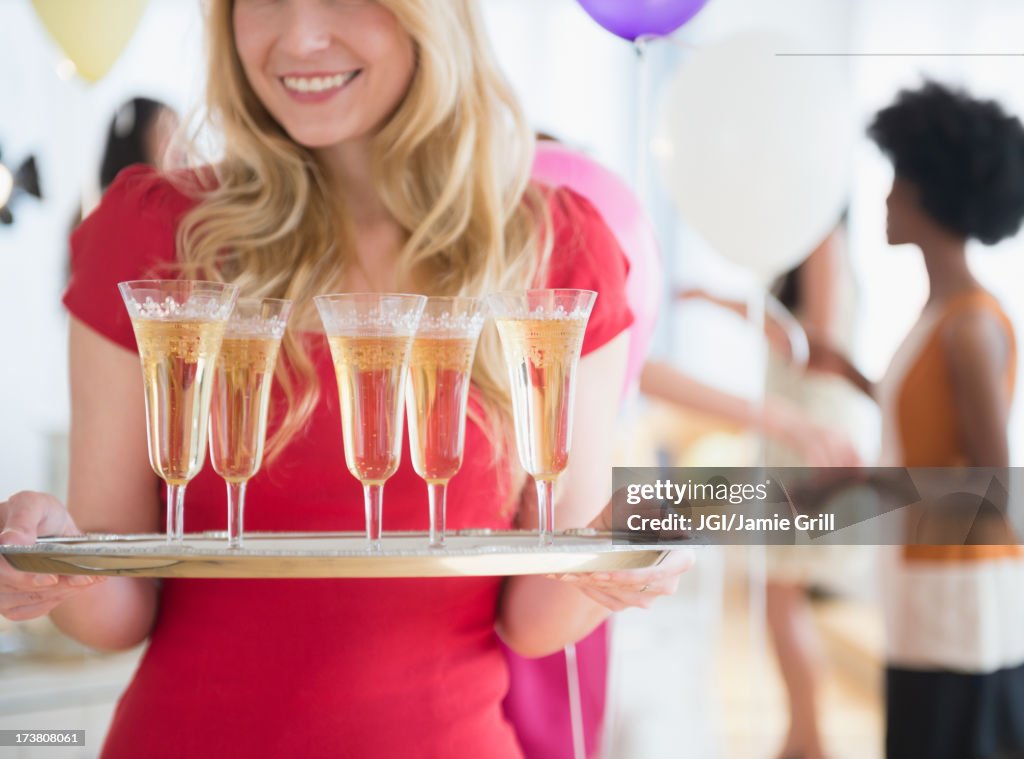 Smiling woman carrying tray of champagne