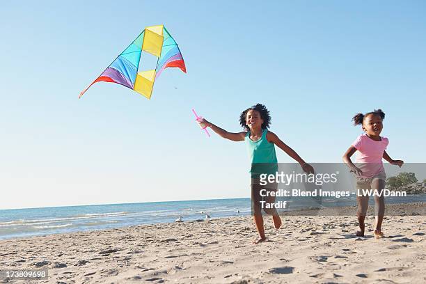 black girls flying kites on beach - alleen kinderen stockfoto's en -beelden