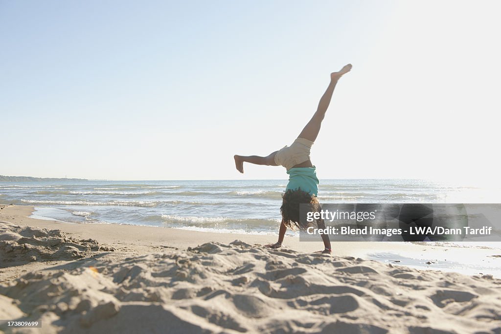 Black girl doing cartwheels on beach