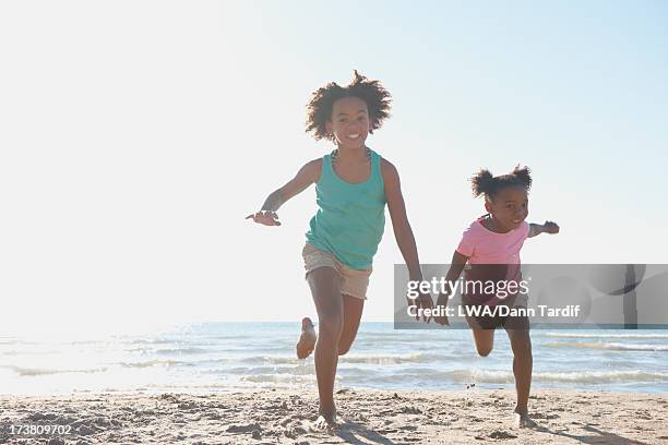 black girls running on beach - running toronto stock-fotos und bilder