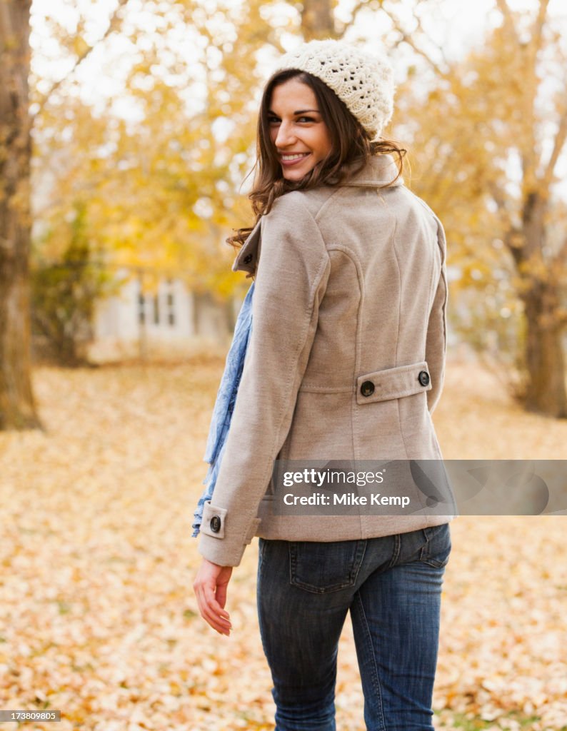 Caucasian woman walking in autumn leaves