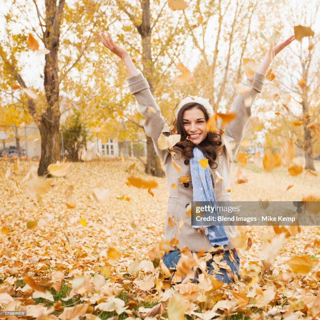 Caucasian woman playing in autumn leaves