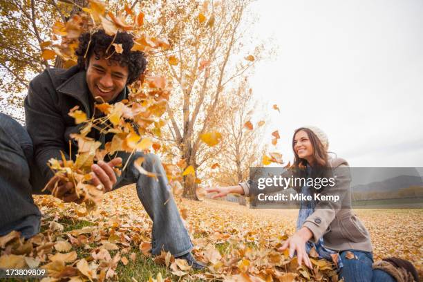 couple playing in autumn leaves - veralbern stock-fotos und bilder