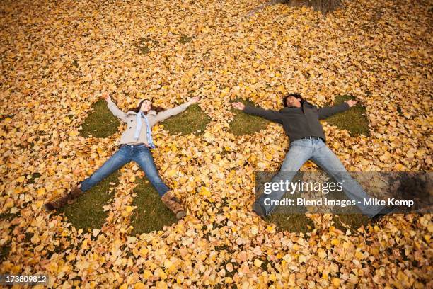 couple making angel in autumn leaves - man angel wings stock pictures, royalty-free photos & images
