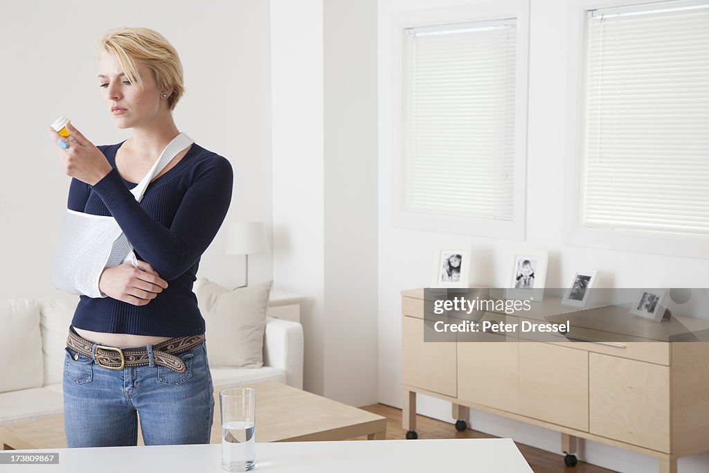 Caucasian woman with broken arm reading pill bottle