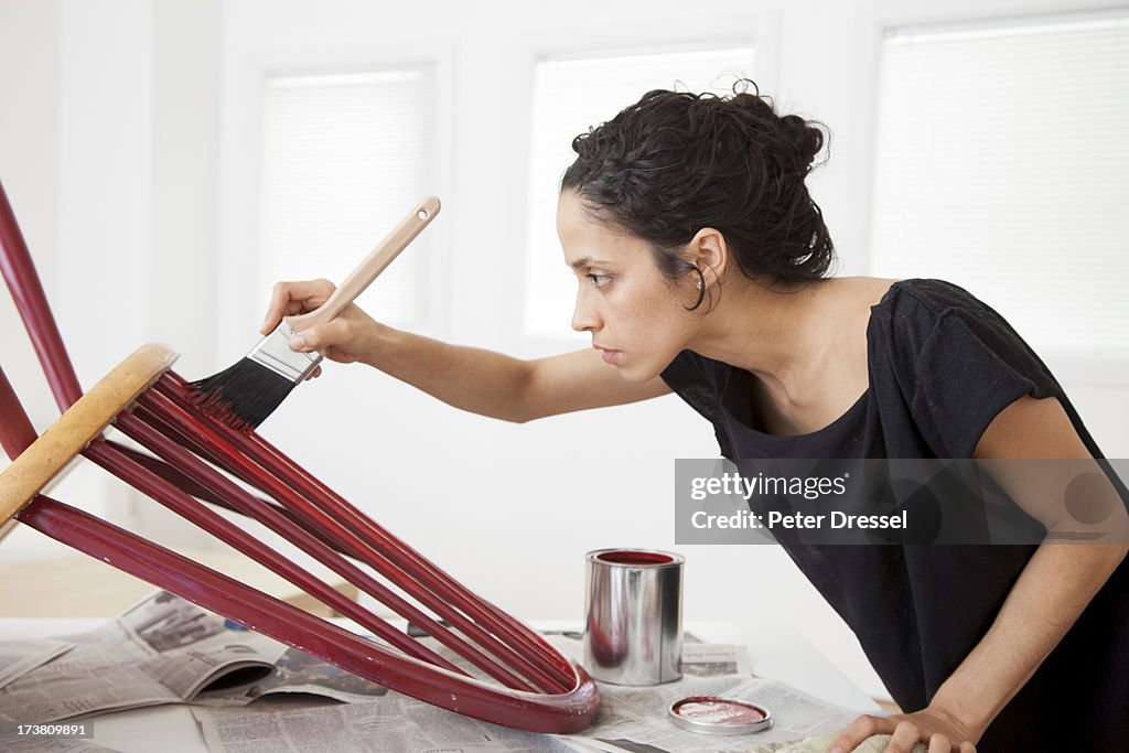 Hispanic woman painting chair