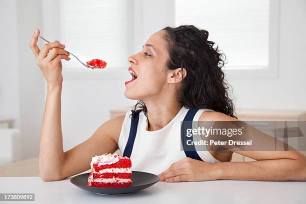 hispanic woman eating cake in kitchen - mouth open profile stock pictures, royalty-free photos & images