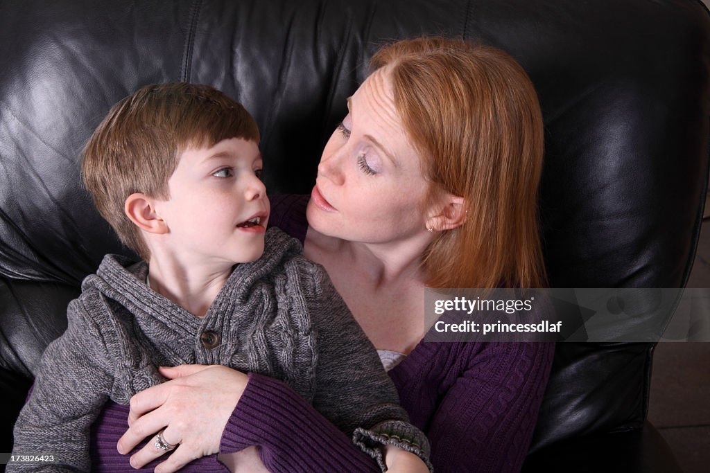 Mother and son talking while lying on leather sofa