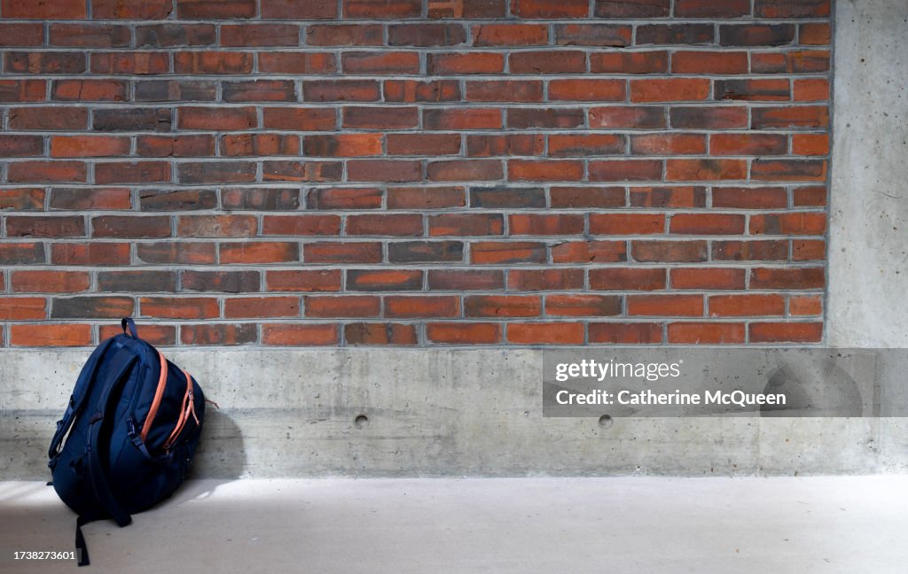 Single student backpack in front of brick wall