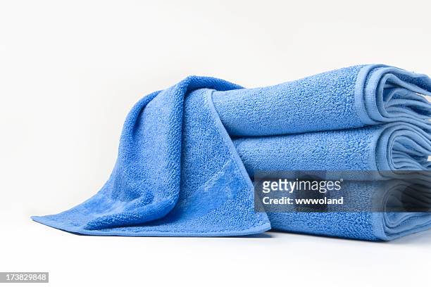 stack of folded blue cotton towels with one draped on top - towel stock pictures, royalty-free photos & images