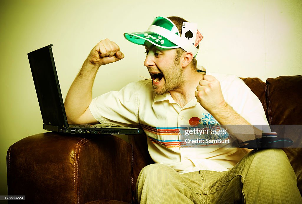 Internet poker player with visor cheering at laptop