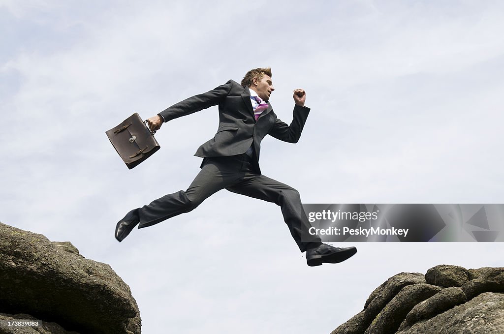 Geschäftsmann springen im Freien zwischen den Felsen und hartem Ort White Sky
