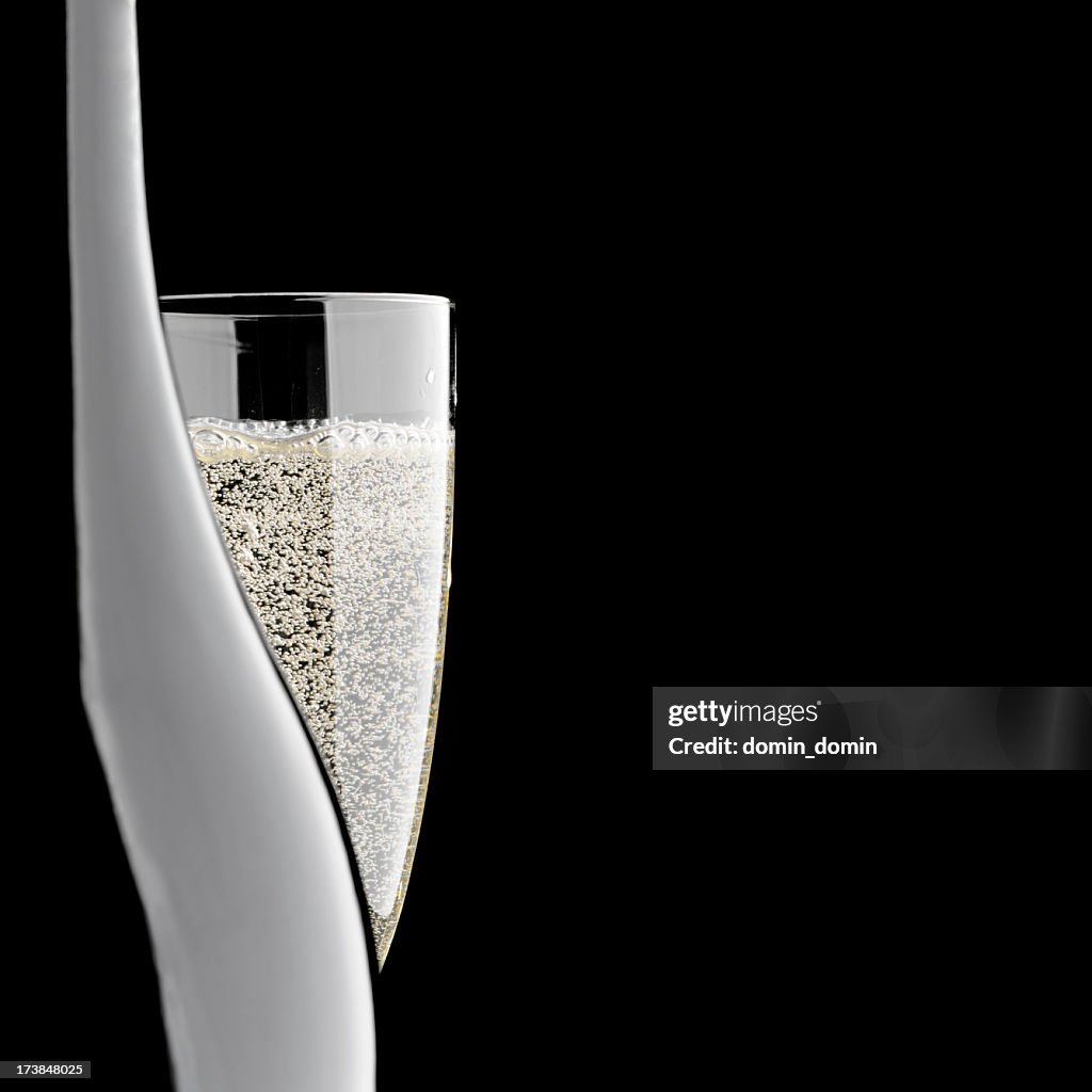 Close-up of champagne bottle and glass, isolated on black background