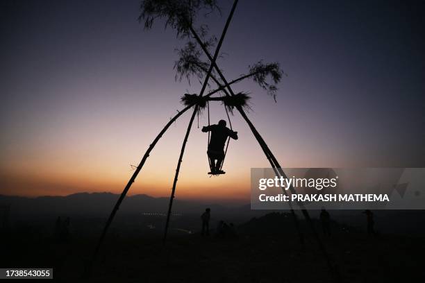 Boy sways on a swing traditionally called the 'Dashain Ping' on the occasion of the Nepali Hindu festival 'Dashain' near the Changu Narayan temple in...