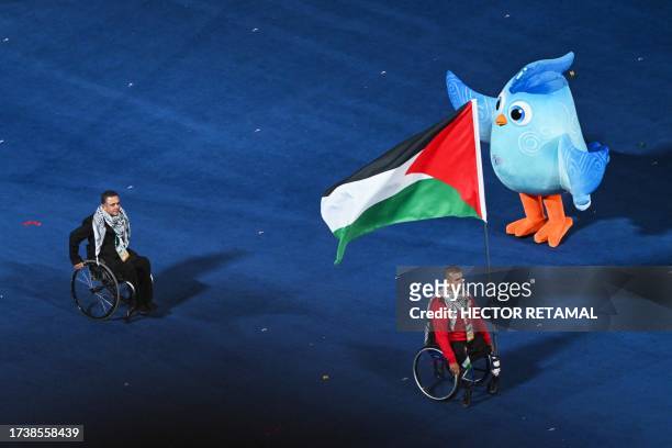 Palestinian delegate carries their country's national flag as he takes part in the athletes parade during the opening ceremony of the 2022 Asian Para...