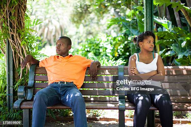 young couple sitting on park bench ignoring each other. cape town, western cape province, south africa - communication problems photos et images de collection