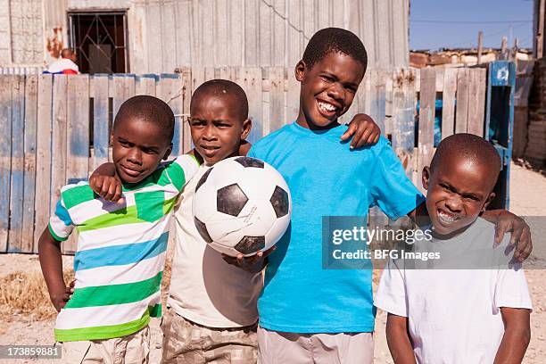 vier jungen in den township mit einem fußball-ball, cape - poor kids playing soccer stock-fotos und bilder