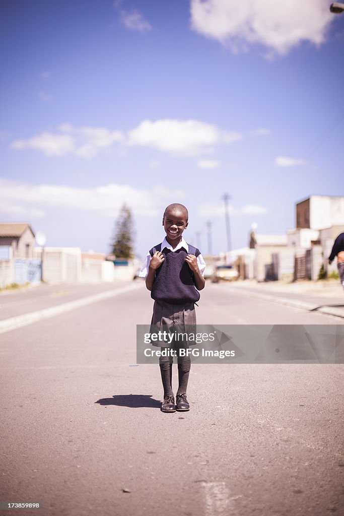 Young school boy standing proudly in street in township