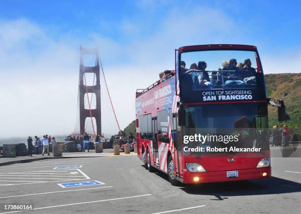 Visitors and other tourists on an open top sightseeing bus enjoy a stop at the north end of the Golden Gate Bridge in San Francisco, California.