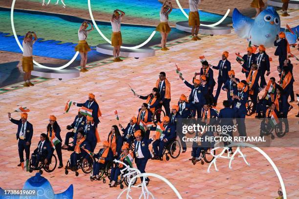 India's delegation wave their country's national flag as they take part in the athletes parade during the opening ceremony of the 2022 Asian Para...