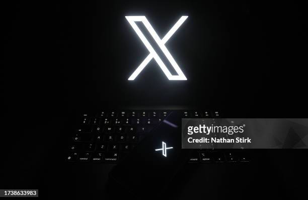 The logo of online social media site 'X' is displayed on a smartphone and laptop on October 16, 2023 in Holmes Chapel, United Kingdom.