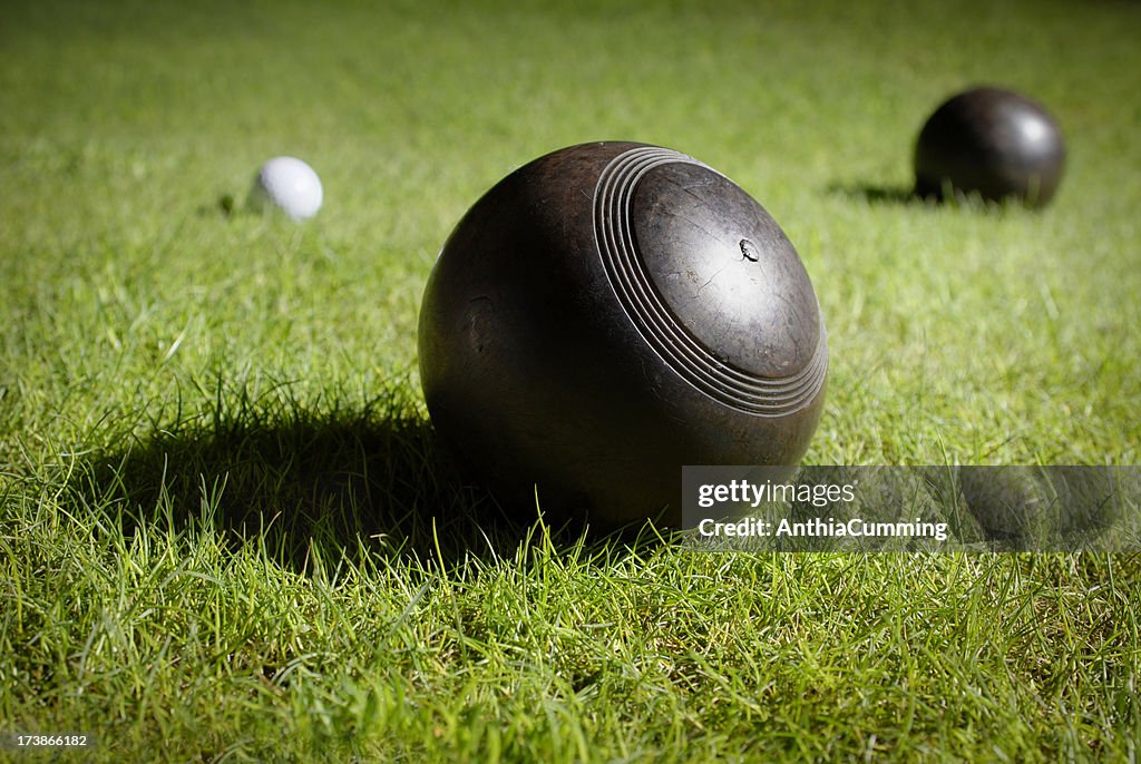 Wooden lawn bowls on a bowling green around jack