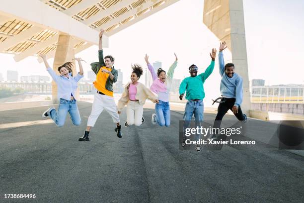 group of multiracial young friends having fun jumping together over urban background. millennial people enjoying time together celebrating outside. happiness, friendship and youth community concept. - saltar actividad física fotografías e imágenes de stock