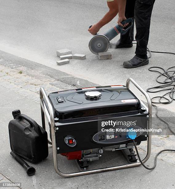electrical generator in foreground and man using masonry saw - generator stock pictures, royalty-free photos & images