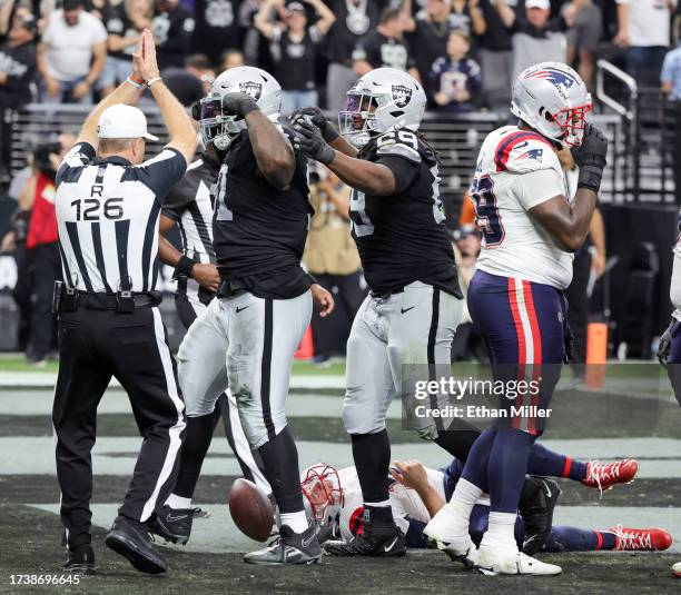 Defensive tackles Bilal Nichols and Adam Butler of the Las Vegas Raiders celebrate after Nichols sacked quarterback Mac Jones of the New England...