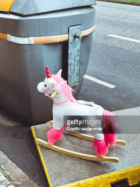 a rocking unicorn in the trash - niñez stockfoto's en -beelden