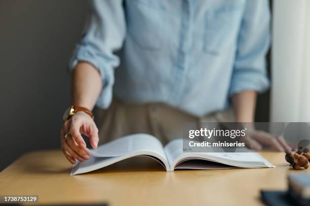 an unrecognizable woman turning pages of a book in a library - turning page stock pictures, royalty-free photos & images