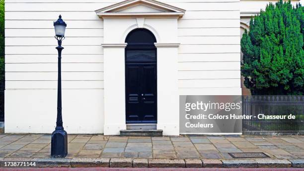 entrance door with triangular tympanum of a georgian style building with a garden protected by a wrought iron gate, sidewalk and an old street lamp in london, england, united kingdom - street light lamp stock pictures, royalty-free photos & images