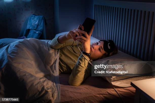 teenage girl suffering sleeping disorders using smartphone at night - child asleep in bedroom at night stock pictures, royalty-free photos & images