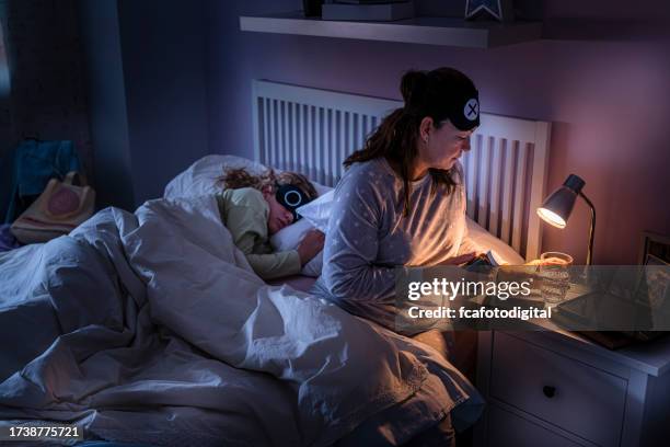 mother taking sleeping pills while daughter is sleeping beside her - bedside table kid asleep stock pictures, royalty-free photos & images