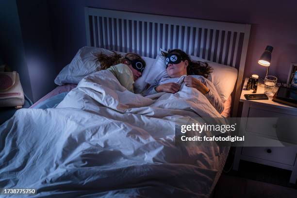 mother and daughter wearing eye masks fell asleep - bedside table kid asleep stock pictures, royalty-free photos & images