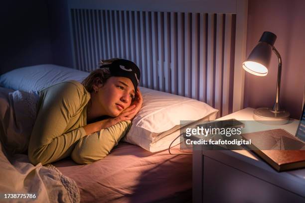 portrait of teenage girl laying in bed suffering insomnia - bedside table kid asleep stock pictures, royalty-free photos & images
