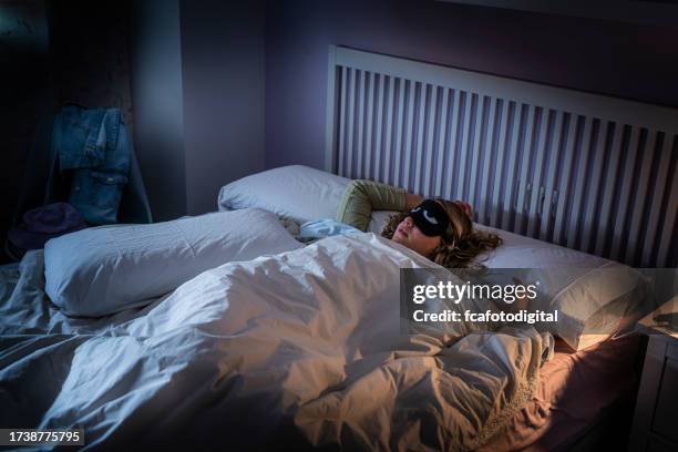 teenage girl using eye mask wrapped in a blanket sleeping pacefully - bedside table kid asleep stock pictures, royalty-free photos & images