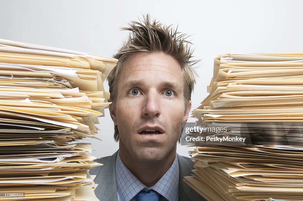 Businessman Office Worker Sits Dazed Between Piles of Paperwork Files