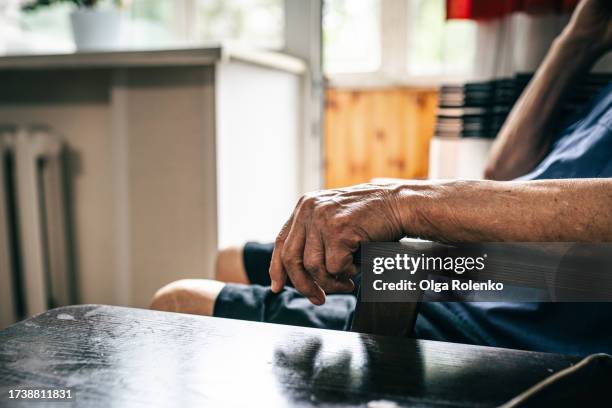 solitude seniors in nursing home. unrecognizable senior man hand leaning on armrest against smoothed bright interior. close up - armlehne stock-fotos und bilder