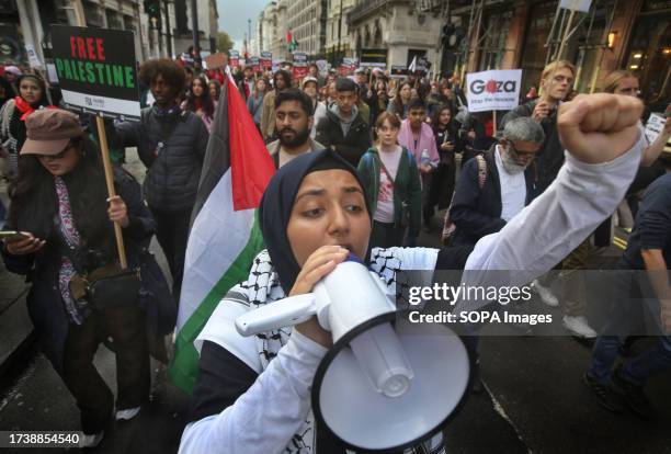Protester punches the air in defiance as she marches across London, chanting slogans into a megaphone. Supporters of Palestine come together to march...