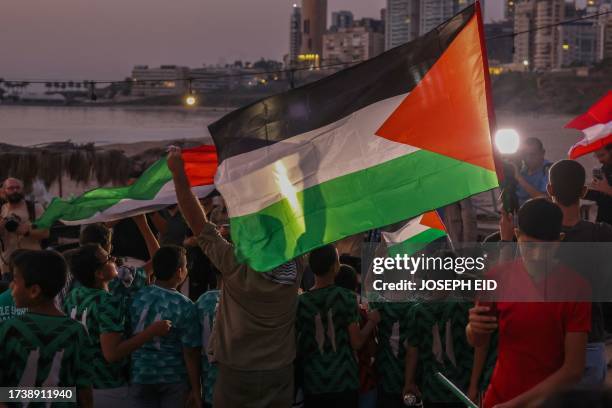 Children lift Palestinian flags during a solidarity vigil organized by Lebanon's Press Photographers Syndicate and the Ajial Social Communication...