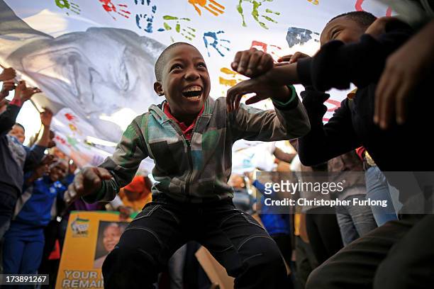 Children dance and celebrate as people wave a banner of Nelson Mandela to celebrate his 95th birthday outside the Mediclinic Heart Hospital where he...