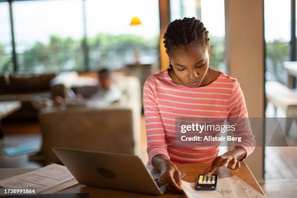 young woman working on home finances - woman calculator stock pictures, royalty-free photos & images