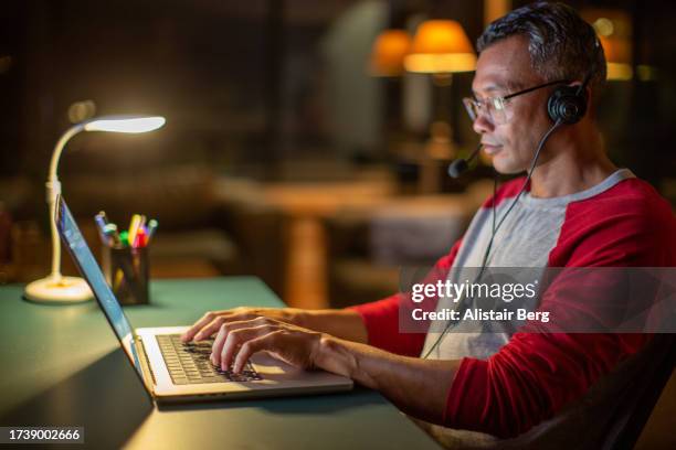 mature man working from home in the evening - avondschool stockfoto's en -beelden