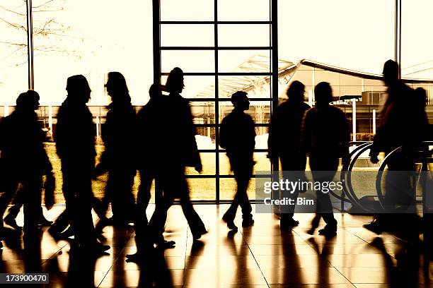 large group of walking people indoors, blurred motion, back lit - group of people silhouette stock pictures, royalty-free photos & images