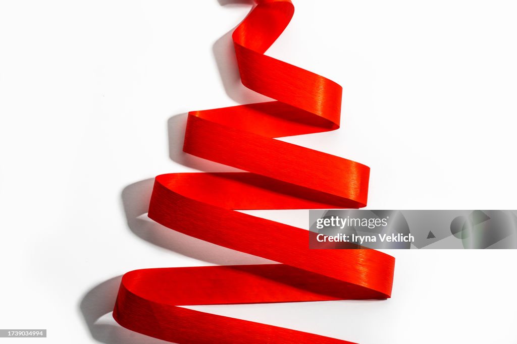 Holiday background made from curly Red Color Satin ribbon in Shape of Christmas Tree on white Background.