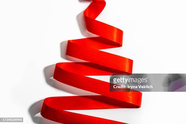 holiday background made from curly red color satin ribbon  in shape of christmas tree on white background. - christmas tree white background stock pictures, royalty-free photos & images