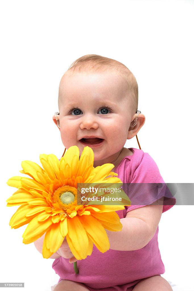 A baby girl in pink holding a flower